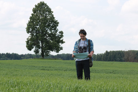 A young man looks at a map in the nature so as not to get lostの写真素材