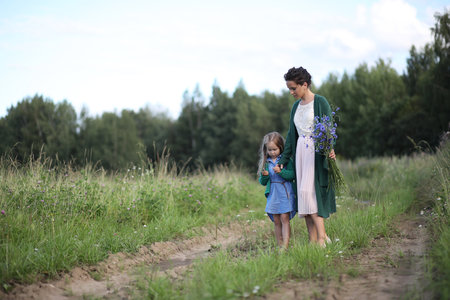 Beautiful young mother with daughter walking on a rural roadの写真素材