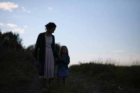 Beautiful young mother with daughter walking on a rural roadの写真素材