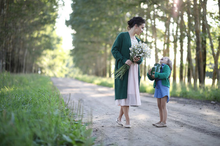 Beautiful young mother with daughter walking on a rural roadの写真素材