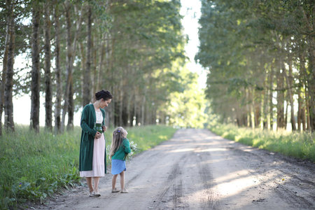 Beautiful young mother with daughter walking on a rural roadの写真素材