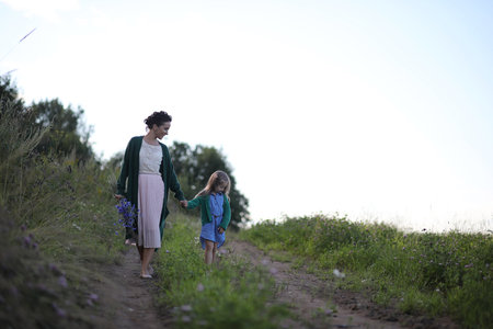 Beautiful young mother with daughter walking on a rural roadの写真素材