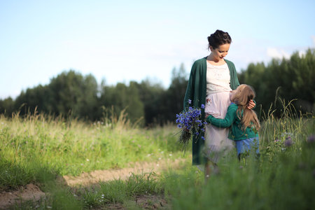 Beautiful young mother with daughter walking on a rural roadの写真素材