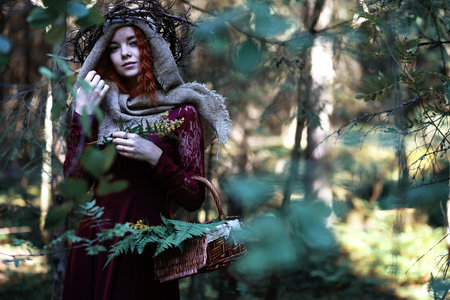The red-haired woman holds a crystal ball in the forestの写真素材