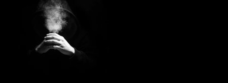 Man in a black hood on a black backgroundの写真素材