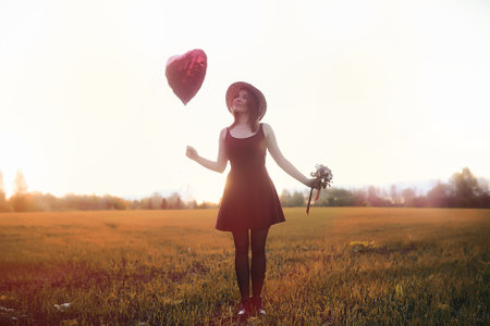 A girl in a hat on a walk in the park. A girl with a basket walks in autumn. Girl is walking along the road at sunset.の写真素材