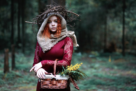 The red-haired woman holds a ritual with a crystal ball in the forestの写真素材