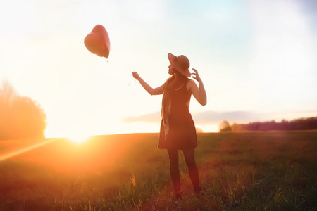A girl in a hat on a walk in the park. A girl with a basket walks in autumn. Girl is walking along the road at sunset.の写真素材