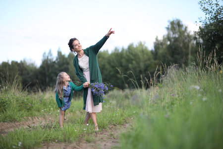 Beautiful young mother with daughter walking on a rural roadの写真素材