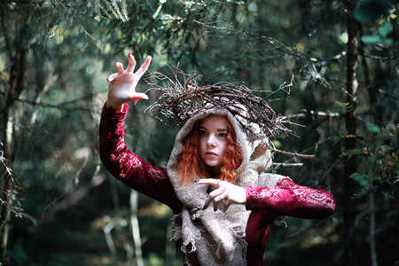 The red-haired witch holds a ritual with a crystal ball in the forestの写真素材