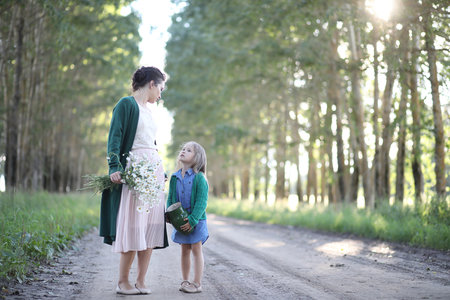 Beautiful young mother with daughter walking on a rural roadの写真素材