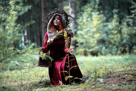 The red-haired woman holds a crystal ball in the forestの写真素材