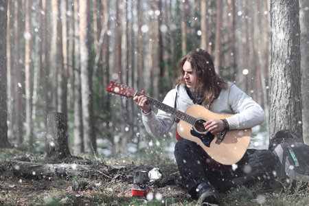 Guitarist in the woods at a picnic. A musician with an acoustic guitar in a tent in the forest. Resting with a guitar outdoorsの写真素材