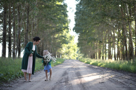 Beautiful young mother with daughter walking on a rural roadの写真素材
