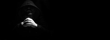 Man in a black hood on a black backgroundの写真素材