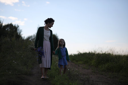 Beautiful young mother with daughter walking on a rural roadの写真素材