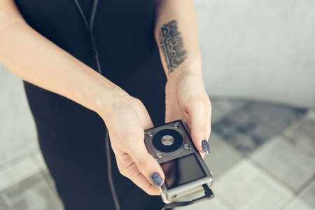 A girl with a tattoo on her arm holds a playerの写真素材