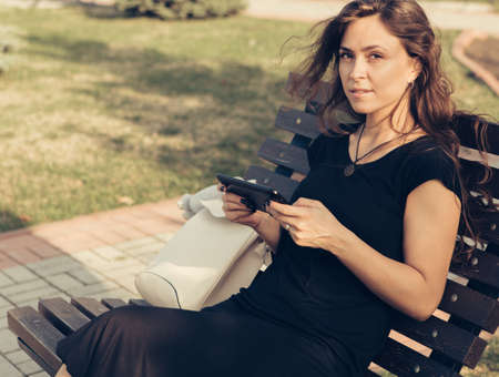 A girl is sitting on a bench holding a tablet