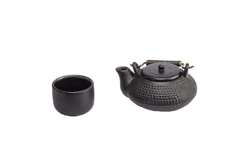 Textured clay teapot for brewing tea and a cup. The teapot hangs over the cup on a slope. Isolate.の写真素材