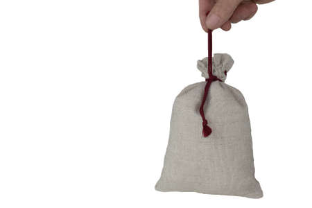 A bag of coarse fabric tied with a rope, fingers hold the bag by a rope, isolate on white. の写真素材