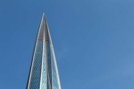 The spire of the office building is made of glass against the blue sky.の写真素材