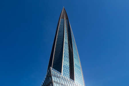 The spire of the office building is made of glass against the blue sky.の写真素材