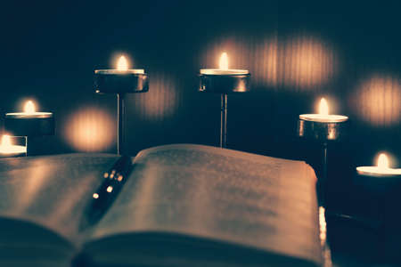 An open book in the light of burning candles. A dark and cozy atmosphere in the library. Reading, education, self-development.の写真素材