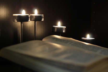 An open book in the light of burning candles. A dark and cozy atmosphere in the library. Reading, education, self-development.の写真素材