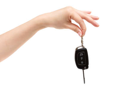 Female hand holds car keys on white background.
