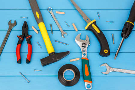 View of straggly work tools laying on blue wooden background.