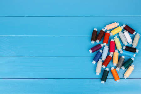 Spools of thread, randomly lying on a blue wooden background.の写真素材
