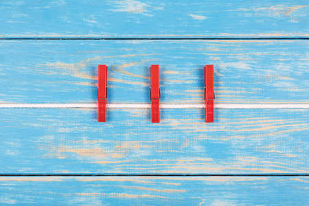 View of red clothespins hanging on a ropeの写真素材
