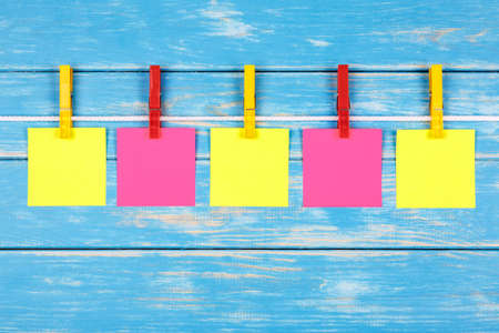 View of five yellow and red clothespins hanging on a rope with five cards on a blue backgroundの写真素材