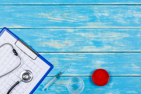 Stethoscope, hype, opened container and an electrocardiogram with a tablet on a blue wooden background.の写真素材