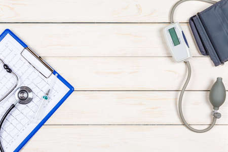 Stethoscope, blood pressure meter, an electrocardiogram and hype on a white wooden background.の写真素材