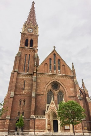 Christian church with bell tower, christian church with red bricks on a cloudy sky background, clock tower with a spireのeditorial素材