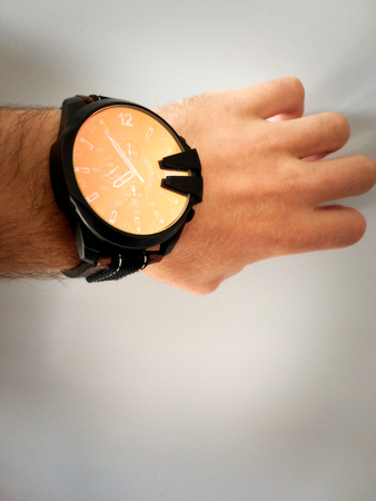 big watch on a white man's hand, watch on the arm, part of the body, white skin, white background, hair on the arm, part of the hand, look at what timeの写真素材