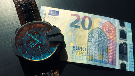 wrist watch with leather strap near the banknote on a dark backgroundの写真素材