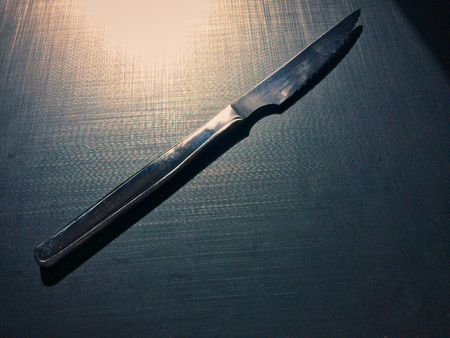 full metal table knife on a dark background, table knife, cutlery, dark background, metallic materialの写真素材