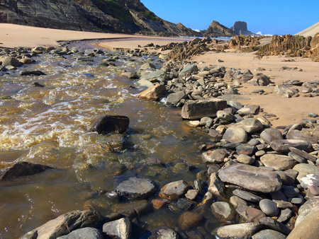 small river flows into the ocean, fast stream flows to the sea, beautiful landscape, amazing rocksの写真素材