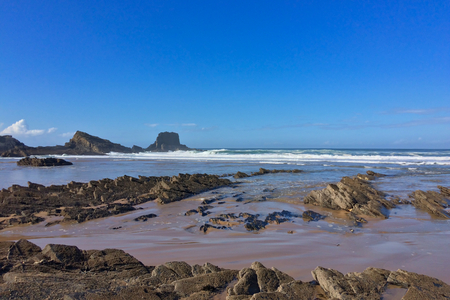 rocks on the ocean, seascape, beautiful sandy beach, clear blue sky, sunny weatherの写真素材