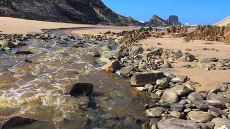 small river flows into the ocean, fast stream flows to the sea, beautiful landscape, amazing rocksの写真素材