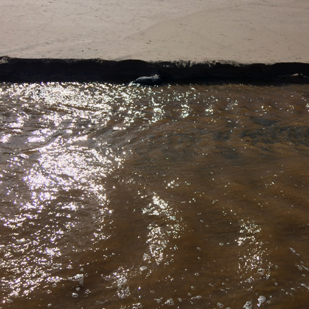 stream with muddy waters, fast flow, sandy shoreの写真素材