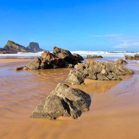 rocks on the ocean, seascape, beautiful sandy beach, clear blue sky, sunny weatherの写真素材
