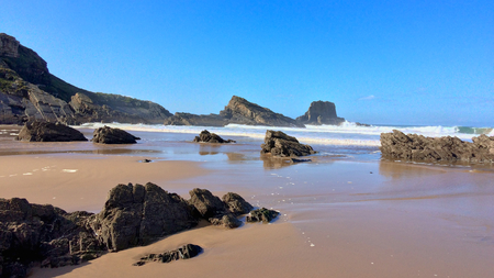 rocks on the ocean, seascape, beautiful sandy beach, clear blue sky, sunny weatherの写真素材