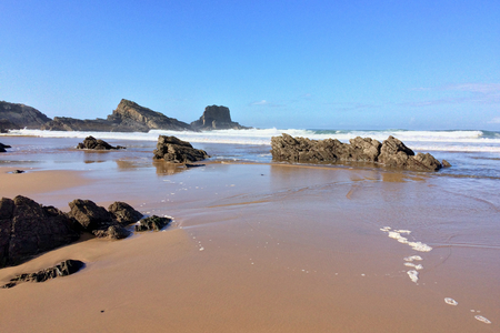 rocks on the ocean, seascape, beautiful sandy beach, clear blue sky, sunny weatherの写真素材