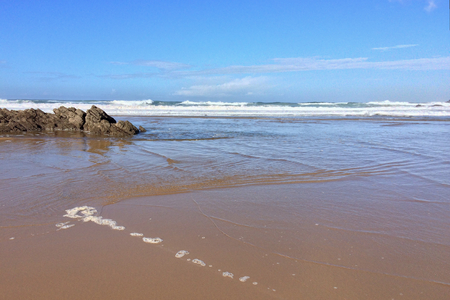 rocks on the ocean, seascape, beautiful sandy beach, clear blue sky, sunny weatherの写真素材
