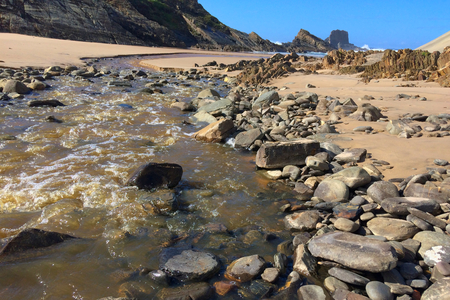 small river flows into the ocean, fast stream flows to the sea, beautiful landscape, amazing rocksの写真素材