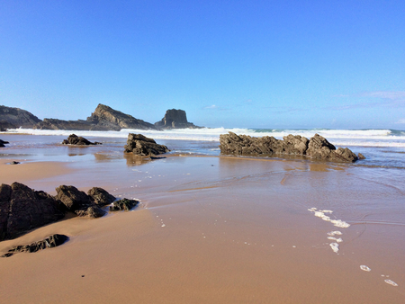 rocks on the ocean, seascape, beautiful sandy beach, clear blue sky, sunny weatherの写真素材