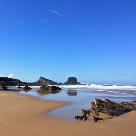 rocks on the ocean, seascape, beautiful sandy beach, clear blue sky, sunny weatherの写真素材